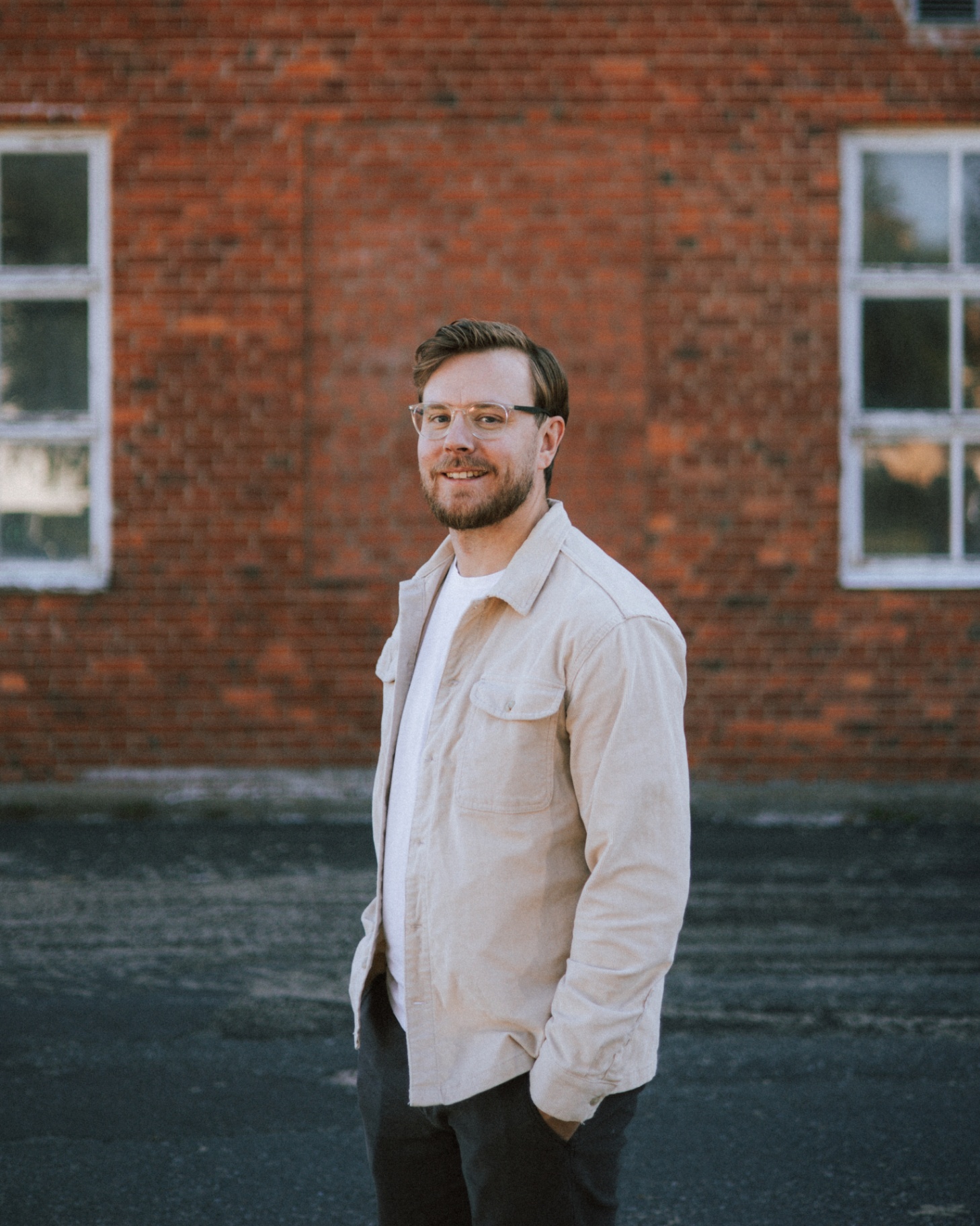 Porträtt av fotograf Daniel Alloh framför tegelvägg i Jönköping.